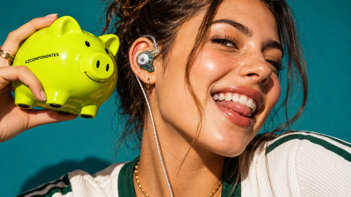Smiling woman wearing wired KZ earphones shaking a lime green piggy bank on a teal background